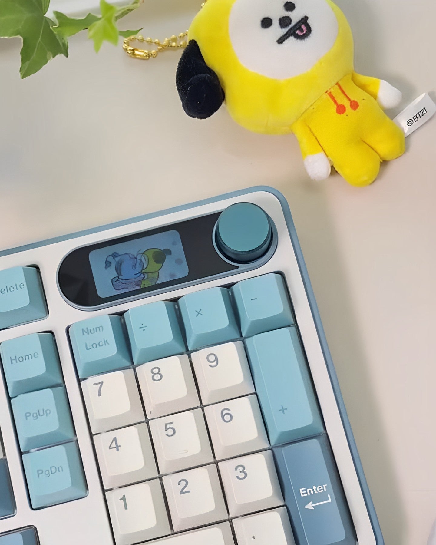 Royal Kludge RK S98 96% compact gaming keyboard on a desk with a cute BT21 character keychain, showcasing a light blue color scheme and unique keycap designs